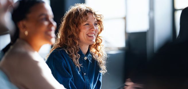Two cheerful coworkers share ideas in a vibrant office setting, fostering a positive and collaborative workplace atmosphere.